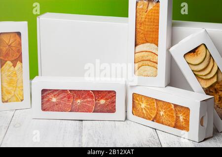 Des boîtes de chips de fruits se trouvent sur un fond en bois blanc, arrière-plan vert clair Banque D'Images