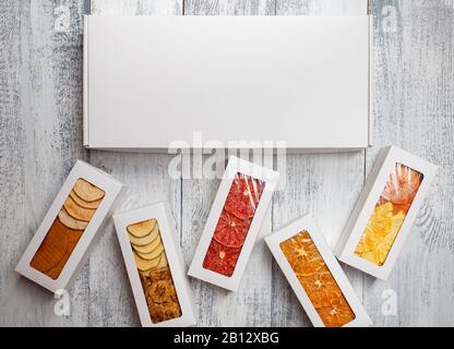 Des boîtes de chips de fruits se trouvent sur un fond en bois blanc Banque D'Images