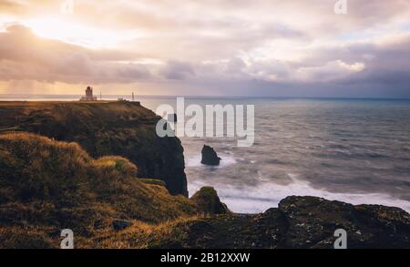 Une longue exposition du phare de Dyrholaey sur une falaise au-dessus de l'océan atlantique sur la côte sud de l'Islande près de Vik. Banque D'Images