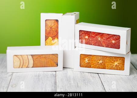 Des boîtes de chips de fruits se trouvent sur un fond en bois blanc, arrière-plan vert clair Banque D'Images