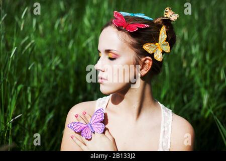 Jeune femme aux yeux clos et papillons artificiels Banque D'Images