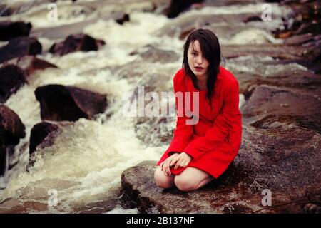 Jeune femme est assise sur un creek Banque D'Images