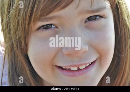 Belle fillette blonde de miel avec des yeux souriants, portrait Banque D'Images