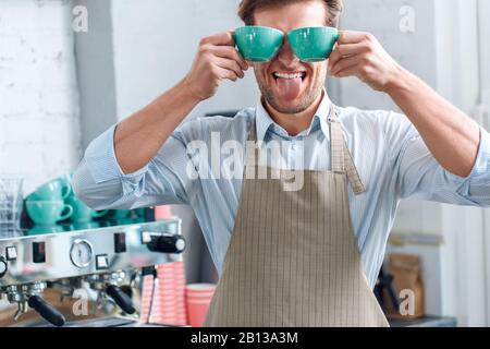 Jeune barista adulte travaillant dans un café, tenant les tasses avec des boissons dans les mains Banque D'Images