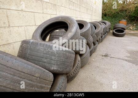 Février 2020 - pile de vieux pneus usés à l'extérieur d'un garage de speed shop Banque D'Images