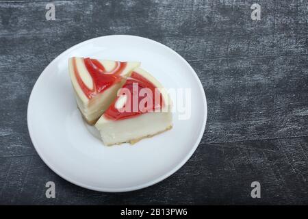 deux morceaux de cheesecake sur une plaque sur fond noir plat en bois. L'image contient de l'espace de copie Banque D'Images