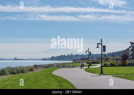 Mt Rainier plane sur le centre-ville de Tacoma et baie de lancement comme vu du point Ruston avec personnes à pied et faire du vélo Banque D'Images