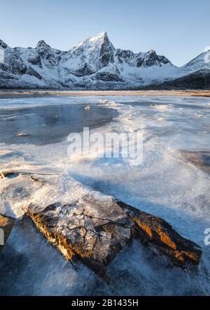 Des fragments de glace irradiée du soleil sur un rocher et d'un seul pic de montagne dans l'arrière-plan, Lofoten, Nordland, Norvège Banque D'Images