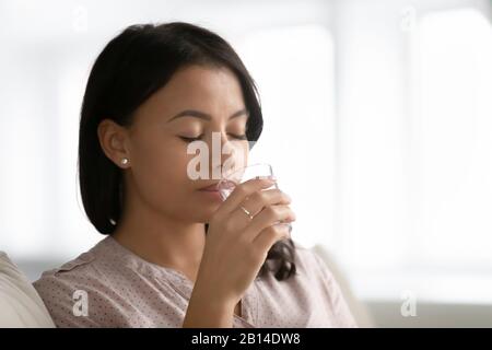 Une femme biraciale boit de l'eau minérale pure à partir de verre Banque D'Images