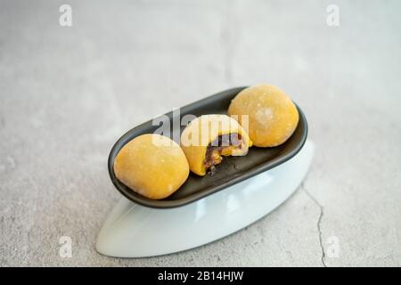 Mochi japonais de couleur jaune dans la pâte de riz et sur fond de béton. Dessert japonais traditionnel. Banque D'Images