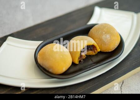 Mochi japonais de couleur jaune dans la pâte de riz et sur fond en bois. Dessert japonais traditionnel. Banque D'Images