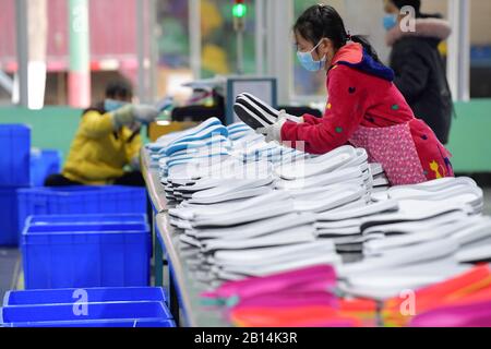 Nanchang, Province Chinoise Du Jiangxi. 22 février 2020. Les travailleurs font des chaussures dans une usine de fabrication de chaussures de la ville de Xiangtang, dans le comté de Nanchang, dans la province du Jiangxi en Chine orientale, le 22 février 2020. De nombreuses entreprises qui comptent sur les exportations ont repris leur production. Crédit: Peng Zhaozhi/Xinhua/Alay Live News Banque D'Images