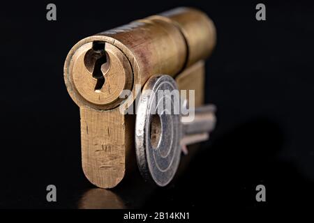 Serrure et clé en laiton verni. Accessoires de fixation des portes avant dans le ménage. Fond sombre. Banque D'Images