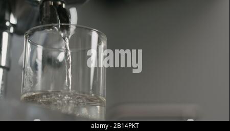 l'eau à faible angle est versée de la machine à café dans un verre, photo large Banque D'Images