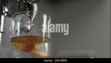 versez à faible angle de la machine à café dans le verre avec de l'eau, photo large Banque D'Images