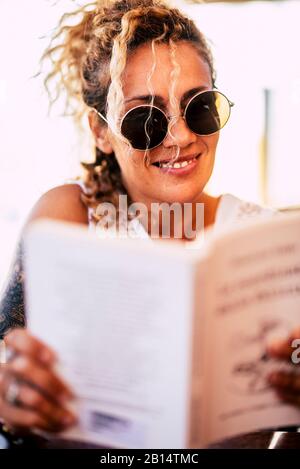 Belle caucasienne jeune femme de 40 ans lire un livre de papier en plein air - se détendre et étudier ou profiter de la lecture - joyeuses personnes et librairie conceps Banque D'Images