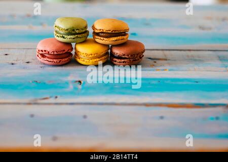 Table en bois bleu avec cinq macarrones savoureux de couleur sur elle - gros plan de la boulangerie - concept de magasin de gâteaux et de crème délicieuse prête à être eate Banque D'Images