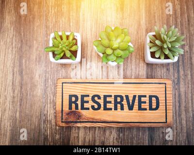 Panneau réservé en bois sur une table en bois dans un restaurant, réservation place au restaurant pour datation sur le concept de jour de fête. Signe réservé de Banque D'Images