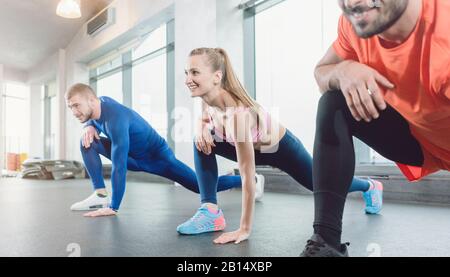 Groupe de personnes dans la salle de gym de cours de fitness s'étirant Banque D'Images