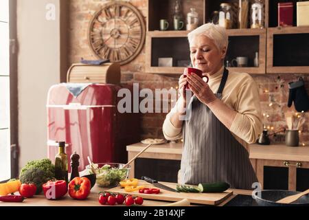 Femme Senior Souriante Se Détendre Avec Une Tasse De Café Dans La Cuisine Banque D'Images