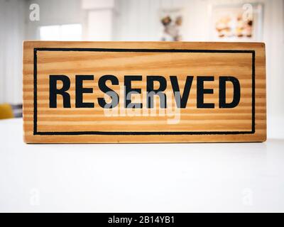 Réservation de place au restaurant pour la rencontre sur le concept de jour de fête. Restaurant avec panneau en bois réservé sur la table blanche avec café décorer les lieux sett Banque D'Images