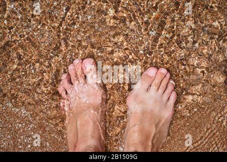 Gros plan sur les jambes pieds nus dans l'eau, vue de dessus Banque D'Images