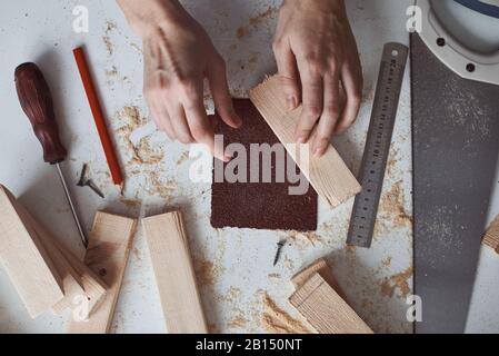 Mains de menuisier polissage des planches en bois avec du papier de verre. Concept de bricolage et de fabrication de meubles Banque D'Images