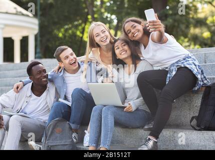 Heureux étudiants multiethniques prenant selfie tout en étudiant en ville Banque D'Images