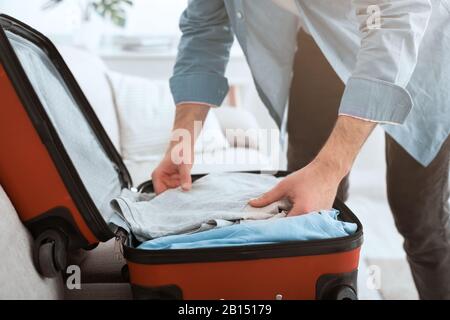 Préparation du voyage. Guy emballe des vêtements dans la valise Banque D'Images