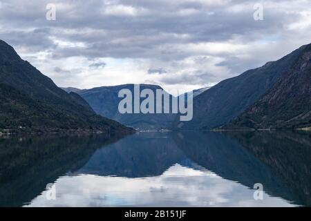Nuages lourds sur le ciel sombre avec réflexion dans le lac des montagnes en Norvège. Soirée aux couleurs bleu foncé en Norvège Banque D'Images