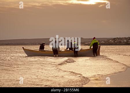 Portobello Beach, Édimbourg, Écosse, Royaume-Uni. 23 février 2020. Départ raisonnablement calme, soleil et température de 3 degrés. Lever de soleil nuageux se brisant au soleil éclatant tôt le matin, le club d'aviron local sur l'eau. Banque D'Images