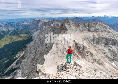 Femme debout sur les rochers et regardant dans le paysage, vue de Birkkarspitze, Karwendeltal, Tyrol, Autriche Banque D'Images