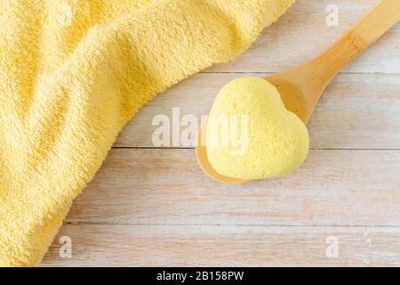 Bath spa composition with bath bombs in spape of heart, sea salt, towels for beauty and body treatment. Healthy relaxation, aromatherapy, body care and aroma massage on wooden background. Natural bath and shower cosmetic concept. Banque D'Images