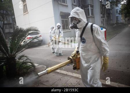 Des volontaires de la communauté chinoise bien protégés désinfectent un quartier résidentiel pour prévenir le nouveau coronavirus et la pneumonie dans la ville de Wuhan, au centre Banque D'Images