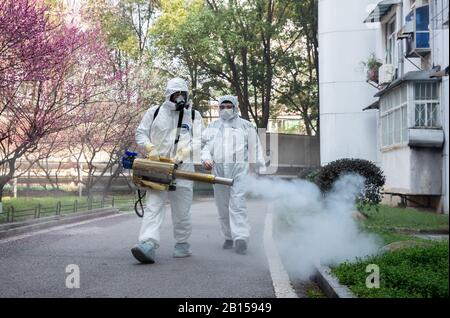 Des volontaires de la communauté chinoise bien protégés désinfectent un quartier résidentiel pour prévenir le nouveau coronavirus et la pneumonie dans la ville de Wuhan, au centre Banque D'Images