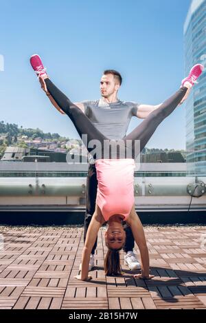 Femme fitness féminin doing handstand, tandis que son entraîneur personnel prend en charge sa. Banque D'Images