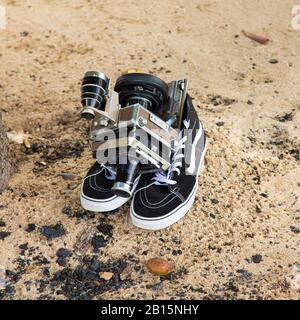LINHOF Universal Sucher Technika film et zoom caméra vidéo sur une paire de sneakers montantes modernes sur une plage de sable Banque D'Images