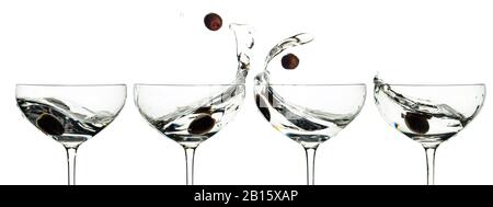 Martini et olives vertes dans des verres avec des éclaboussures isolées sur fond blanc. Banque D'Images