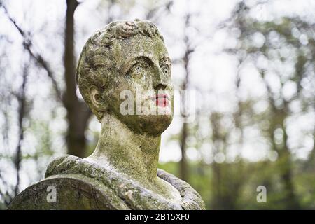 Ancienne statue en pierre dans le parc public de Bruxelles avec lèvres peintes en rouge avec rouge à lèvres ou peinture Banque D'Images