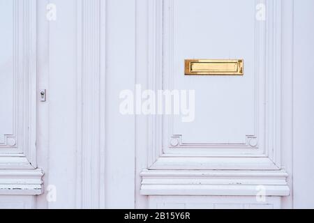 Ancienne boîte aux lettres ou boîte aux lettres en cuivre dans la porte en bois vintage blanche, façon traditionnelle de livrer des lettres, des journaux et de la correspondance à la Banque D'Images