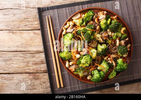 Salade de brocoli rôtie avec shiitake, carottes et noix de cajou dans une assiette sur la table. Vue de dessus horizontale Banque D'Images