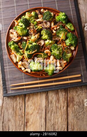 Les champignons shiitake frits chinois, le brocoli, les carottes et les noix de cajou se ferment dans une assiette sur la table. Vue verticale du dessus Banque D'Images