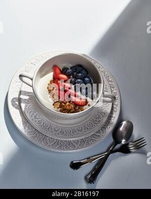 Petit déjeuner sain : yaourt avec fraises fraîches et bleuets, céréales, verre de jus d'orange frais. Banque D'Images