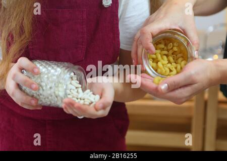 Les mains féminines tiennent des bocaux en verre avec des haricots et des pâtes Banque D'Images