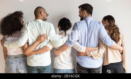 Vue arrière des meilleurs amis multiethniques se tenant debout près du mur gris Banque D'Images