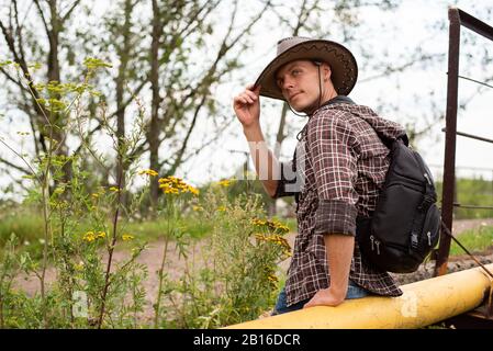 Un homme dans un chapeau de cowboy est assis sur un tuyau de gaz. Banque D'Images