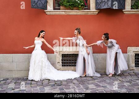 Belle mariée et bridesmaids dans de superbes élégantes robes élégantes en argent gris clair de longueur de plancher dans la vieille belle ville européenne s'amuser sur un Banque D'Images