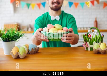 Joyeuses Pâques. Un homme barbu drôle tient un panier avec des œufs et des oreilles de lapin dans la chambre décorée. Banque D'Images