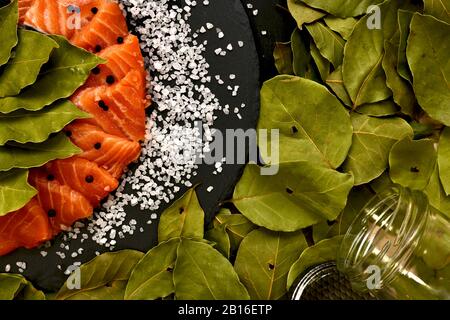 Coupez le poisson rouge fraîchement salé en tranches avec du sel de feuille de laurier grossier et des pois de poivre noir dans un bol. Banque D'Images
