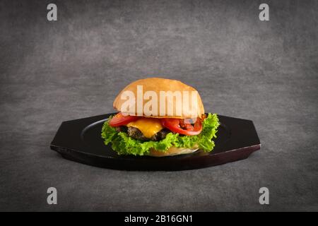 Hamburger au bœuf - hamburger au fromage classique avec patty de bœuf, cornichons, fromage, tomate, oignon, laitue et moutarde au ketchup isolé sur fond gris Banque D'Images